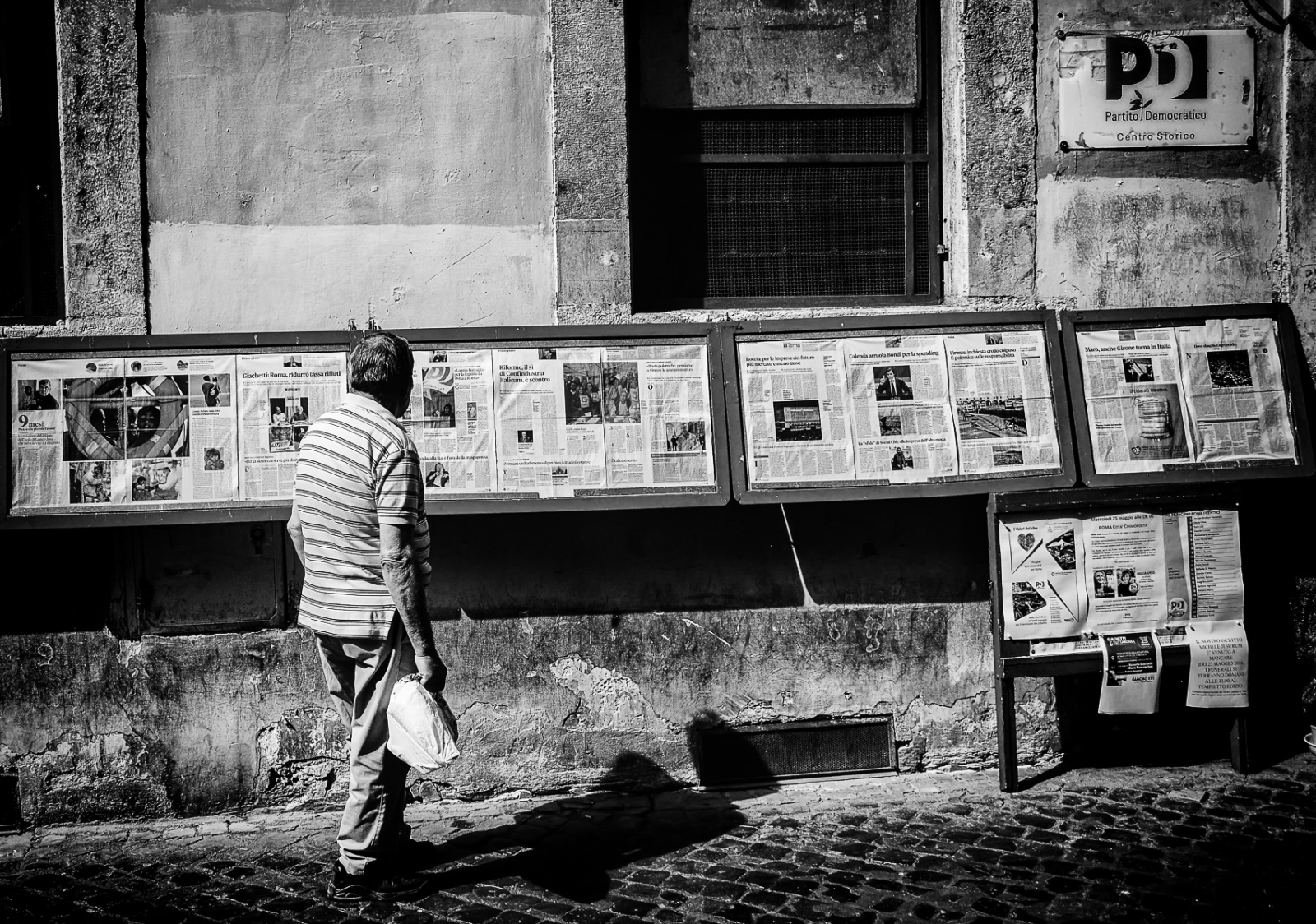 A man contemplating the newspaper outside the PD offices in Via dei Giubbonari